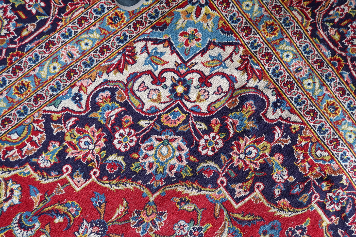 Antique Persian Kashan rug in room-size format (283 × 384 cm), hand-knotted circa 1920s in central Middle Eastern workshop tradition, with a wide navy-ground main border carrying a continuous ivory arabesque and palmette scroll.

