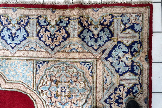 Close-up of the central medallion on a 1930s Persian Kerman carpet, showing a multi-lobed ivory form outlined in dark, with delicate interior floral scroll of small open flowers, curving vine stems, and tiny leaf forms in sky blue, pale pink, olive green, and gold on an ivory ground, with a navy center rosette.

