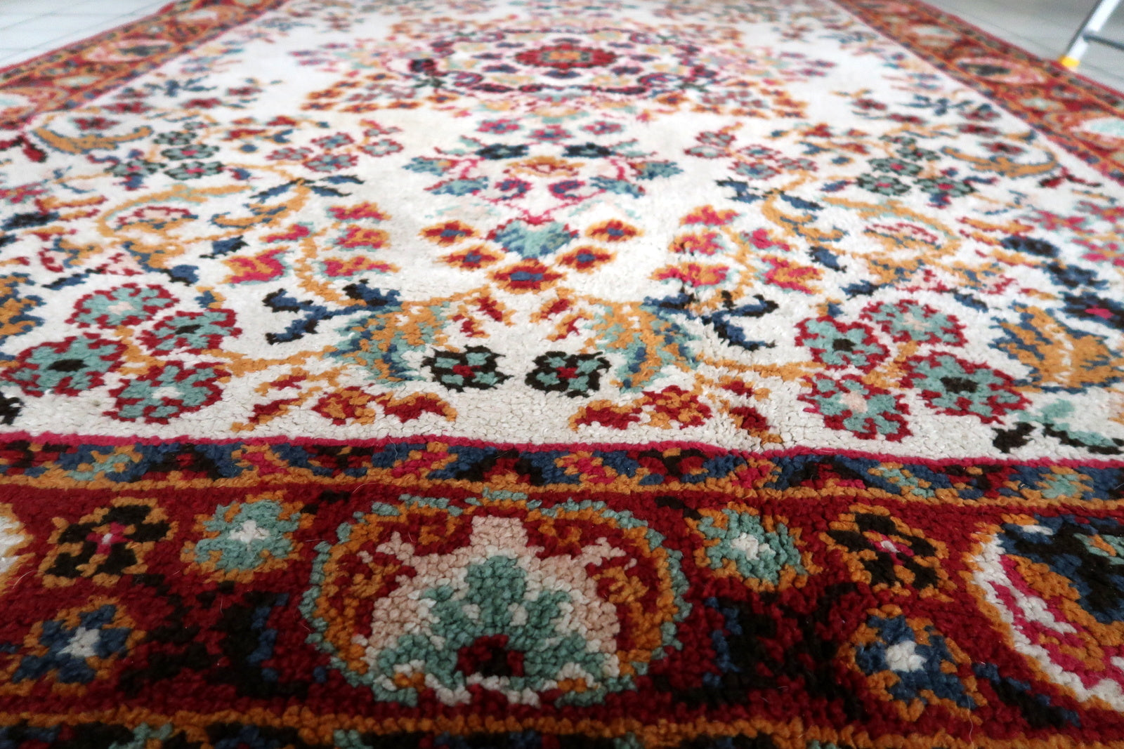 Vintage French decorative rug from the postwar period (c. 1950s), hand-knotted in the Savonnerie tradition with an open ivory field, central crimson rosace medallion, and scattered floral garden – a format that has furnished French châteaux and hôtels particuliers for three centuries.

