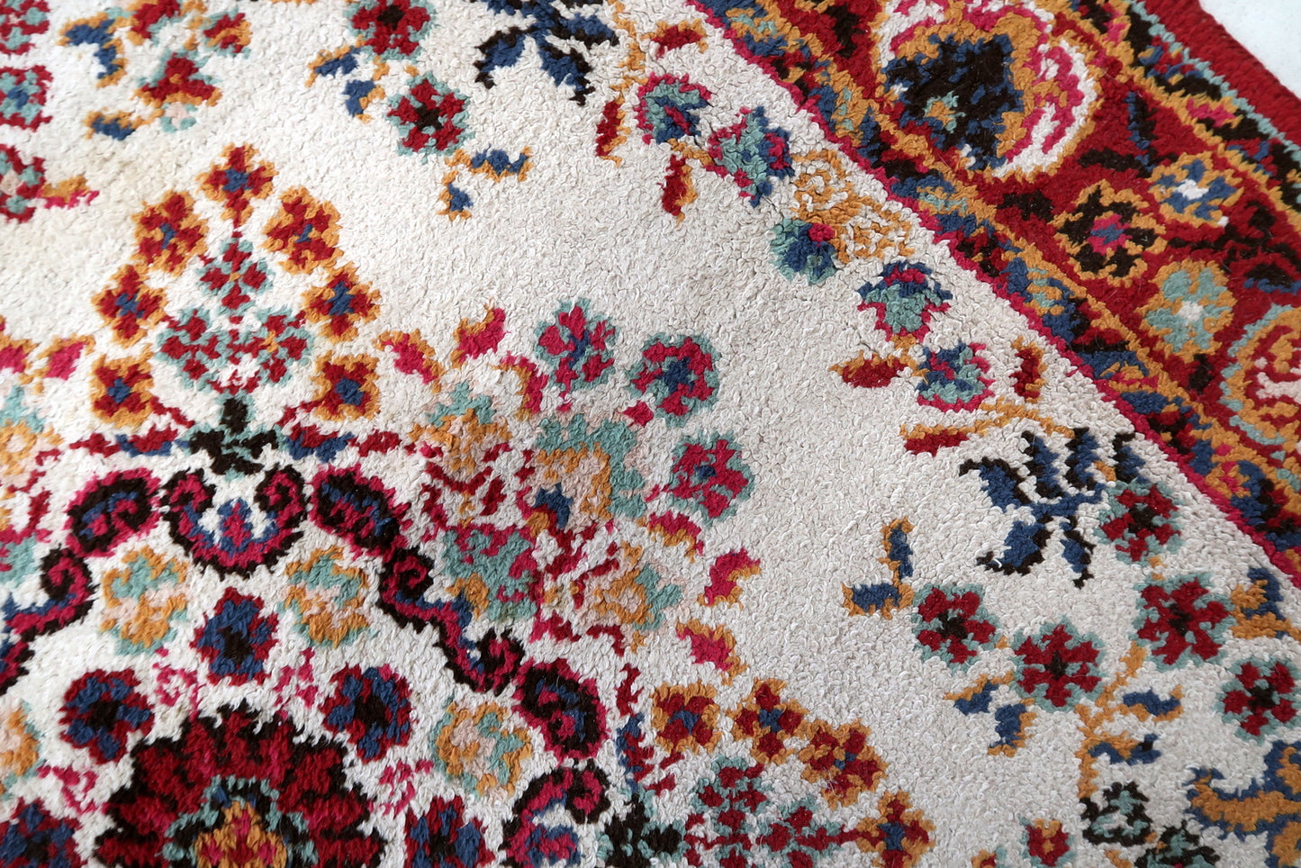 Detail of the corner of a vintage French Savonnerie rug, showing the cleanly resolved corner floral medallion where the crimson main border meets – a mark of quality workshop production – with red wool overcast selvedge intact.

