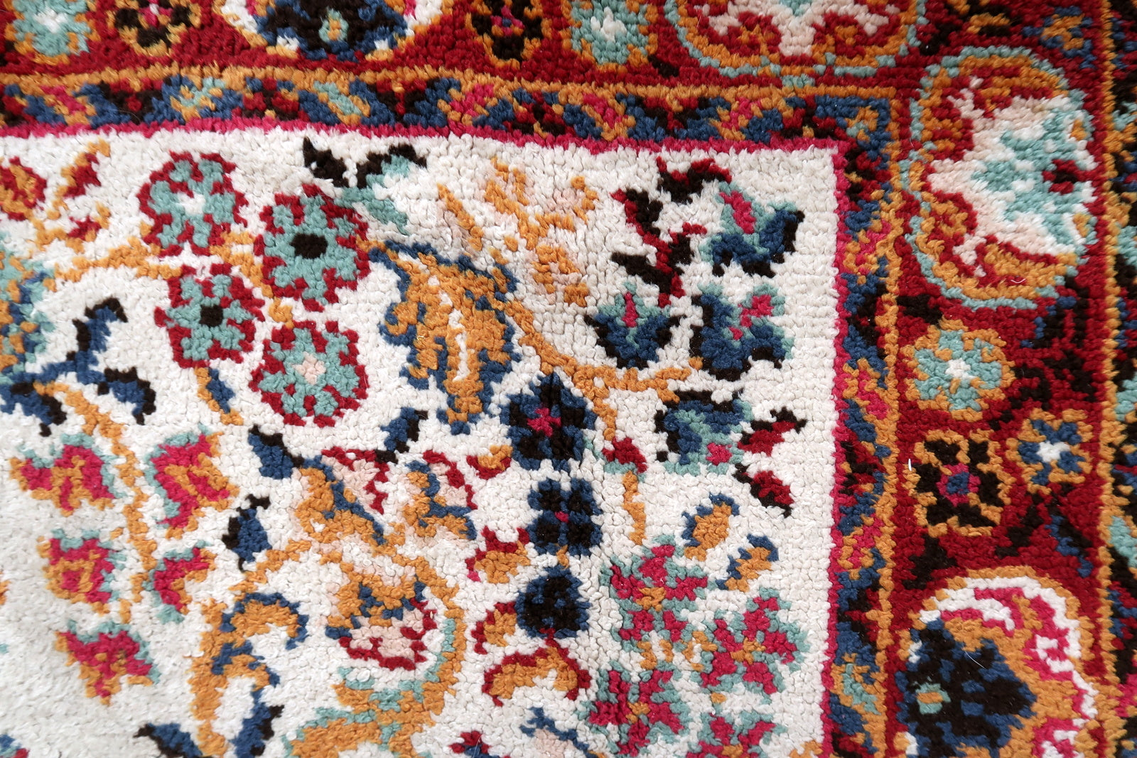 Full view of a vintage Savonnerie-style rug laid flat, showing its rectangular shape, open ivory field with central multi-lobed medallion, scattered floral bouquets, wide crimson border, and teal and navy guard borders.

