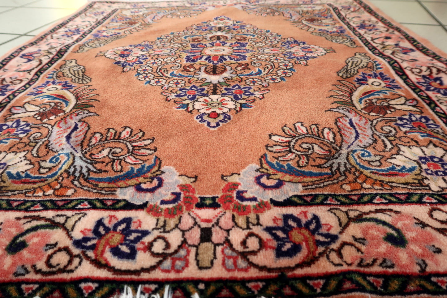 Persian Sarouk rug with warm salmon field and ivory‑pink floral medallion interior

