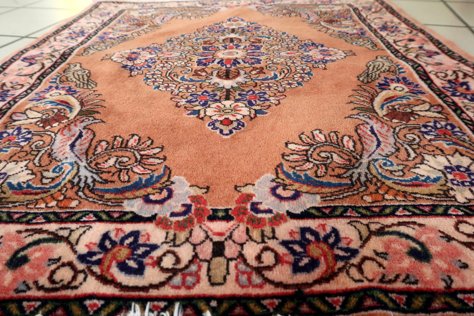 Persian Sarouk rug with warm salmon field and ivory‑pink floral medallion interior

