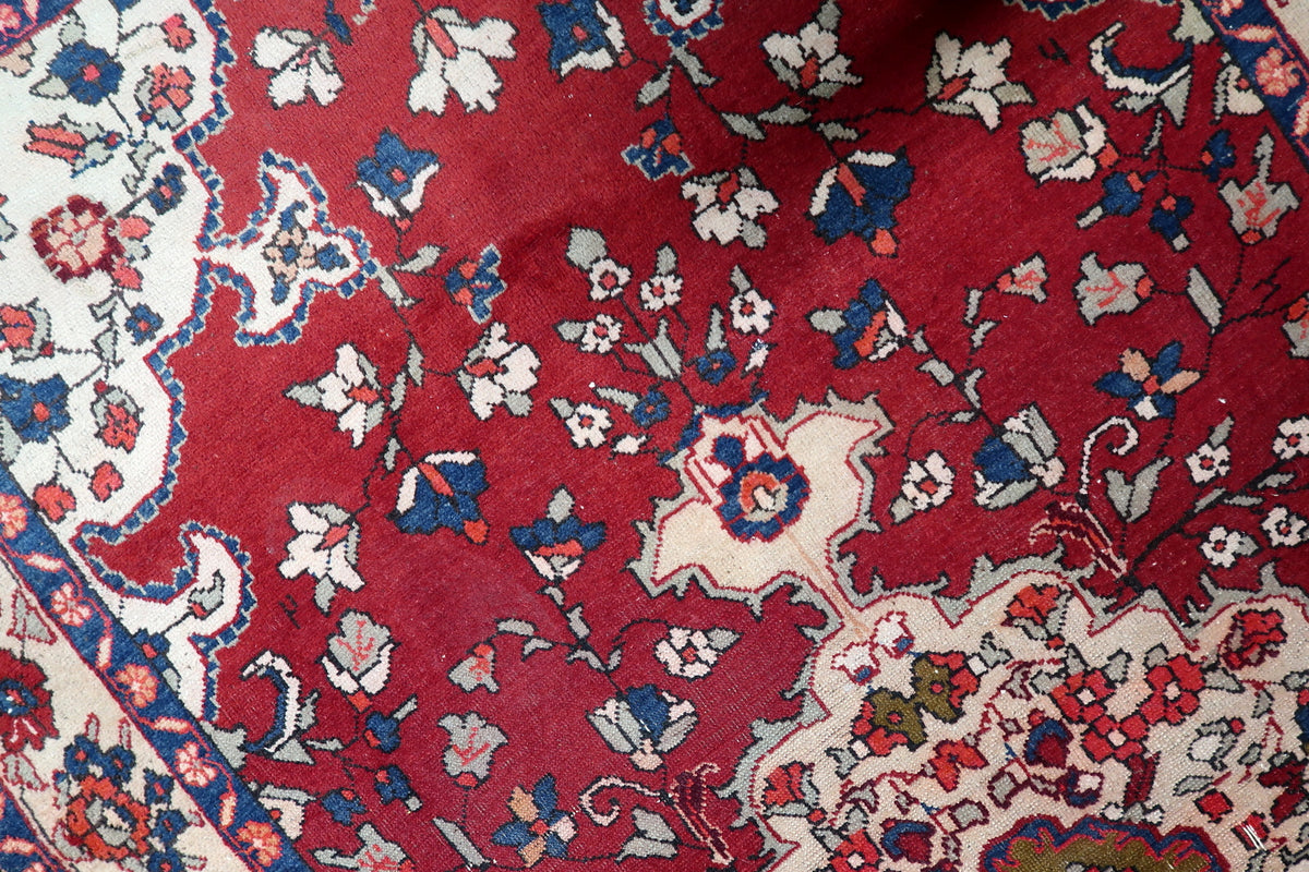 Corner spandrels with stylized palmettes and geometric floral patterns on a hand-woven Persian rug field.