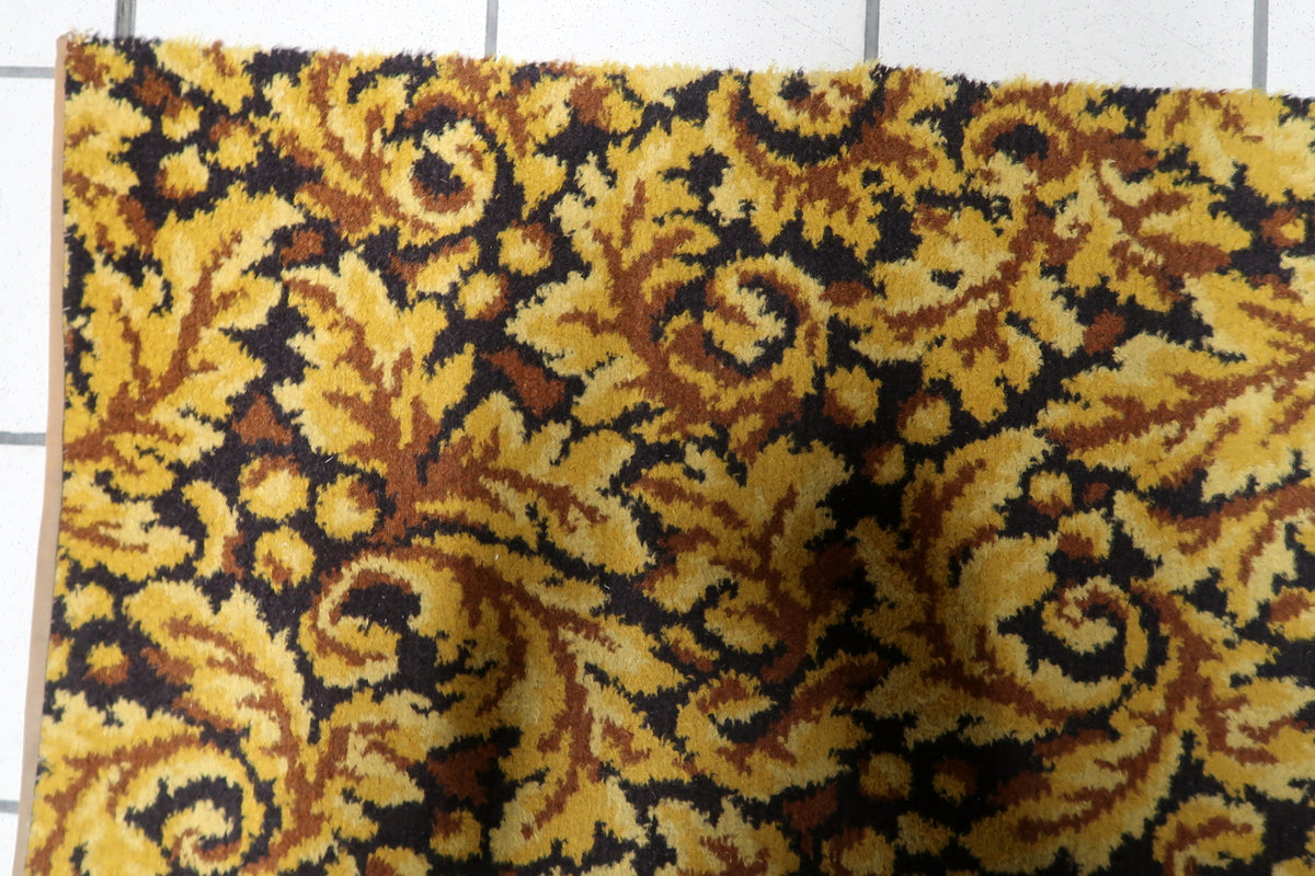 Retro 1960s acrylic accent rug displaying intricate foliate scrollwork, baroque leaf patterns, and gold brown tonal shading.
