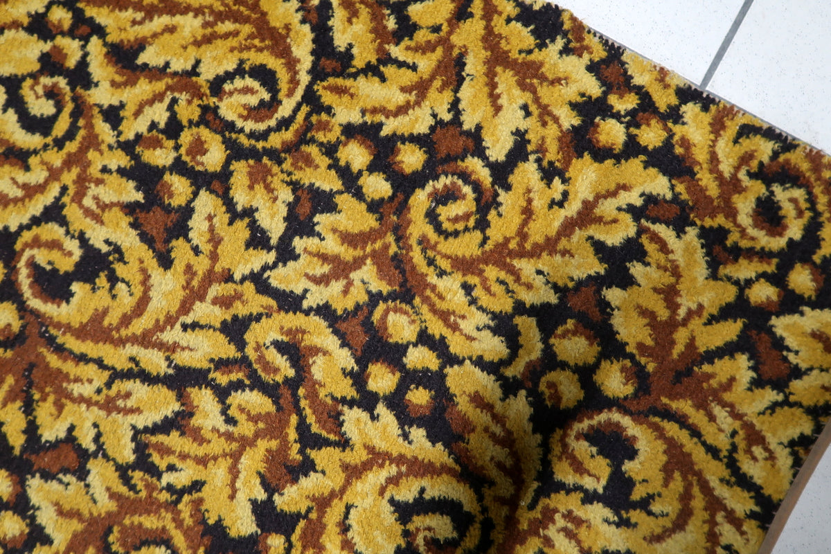 Warm gold and deep chocolate brown color palette on a mid-century German woven acrylic accent carpet.