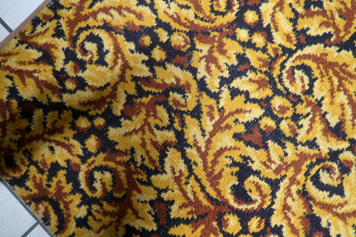 Soft durable synthetic acrylic pile surface on a 1960s vintage European rug with rich ochre and dark brown floral scrolls.