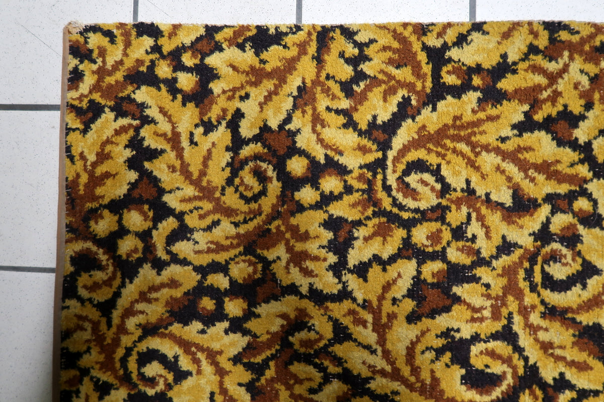 Symmetrical foliate medallion composition framed by ornate scrollwork borders on a 1960s German decorative area rug.