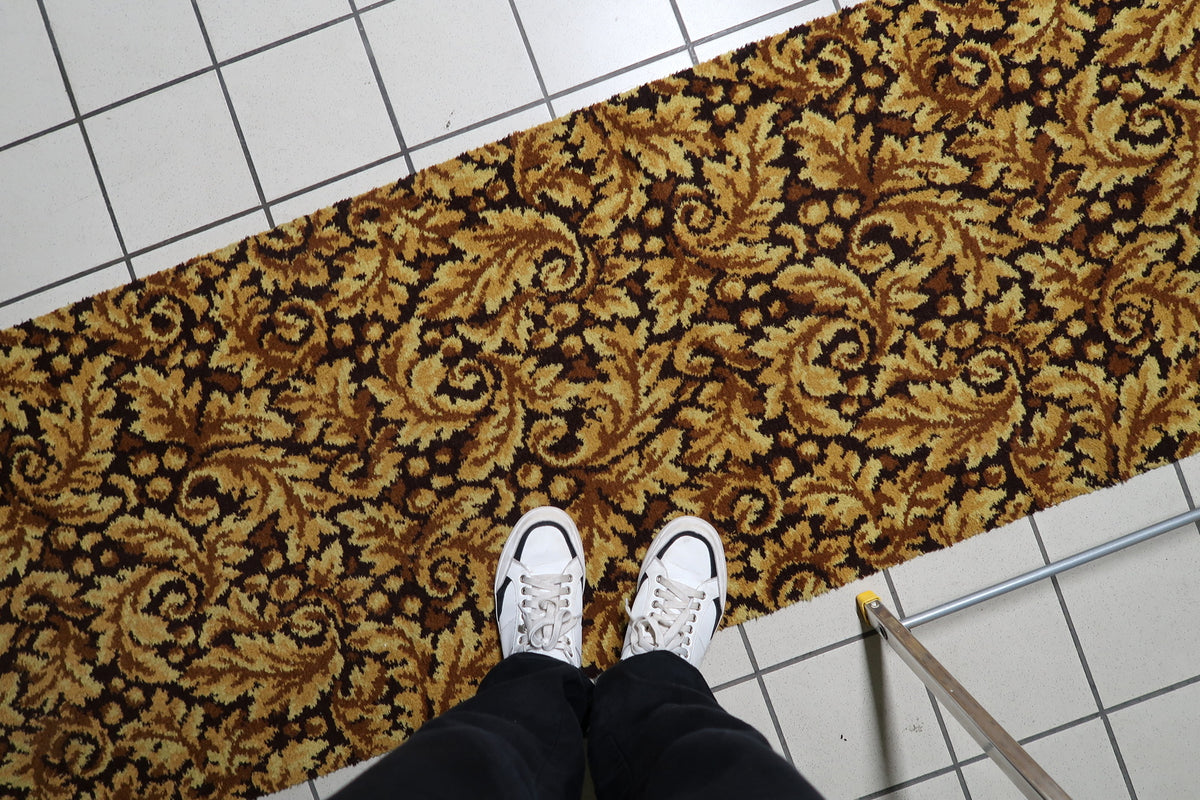 German vintage runner carpet in gold and brown, accented by repeating foliate medallion details