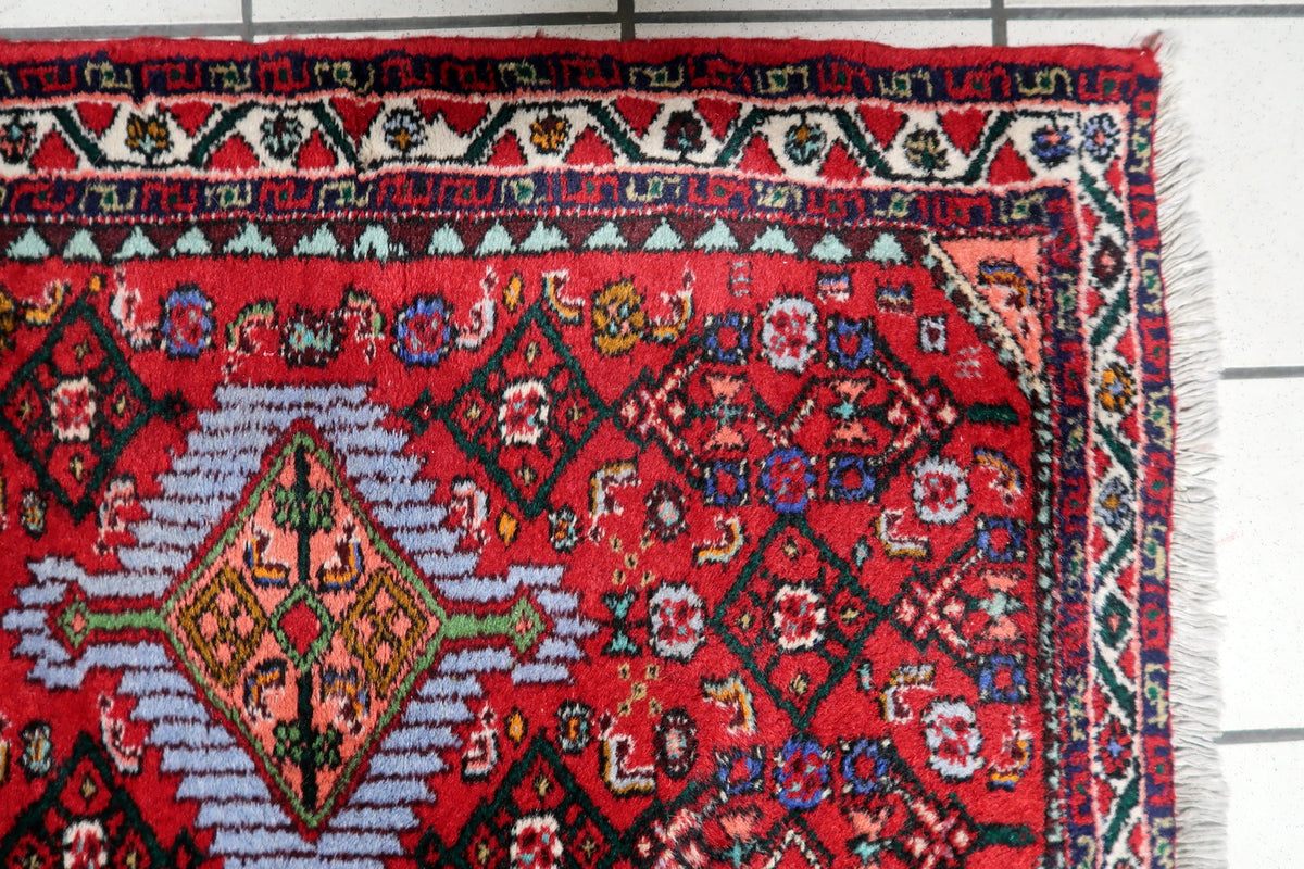 Vintage wool area rug featuring an ornate red medallion surrounded by intricate floral motifs