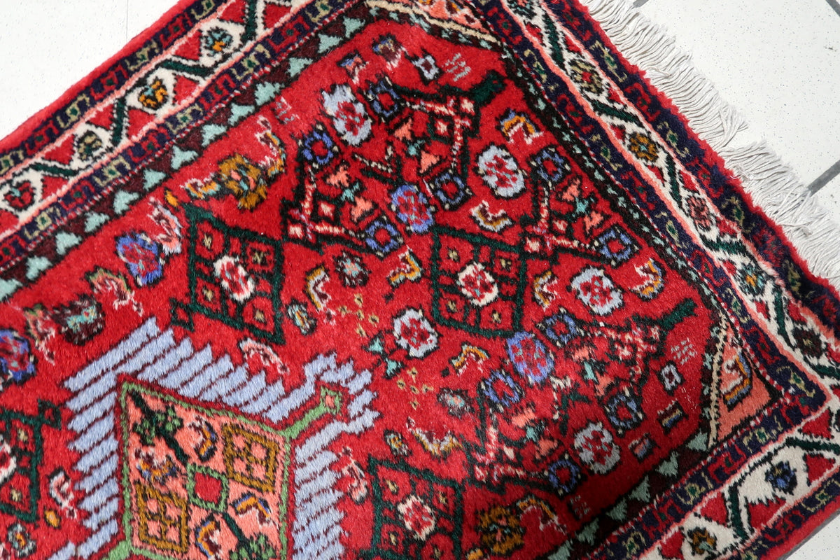 Vintage red wool rug with elegant geometric and floral ornamentation arranged around a central medallion