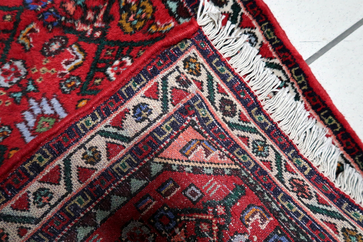 Mid-century handmade rug displaying a richly patterned red ground and refined border design