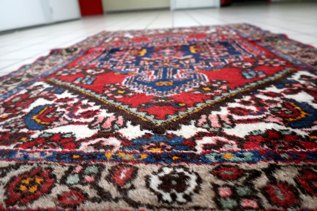 Handwoven wool rug with classic Persian-style design and warm red background