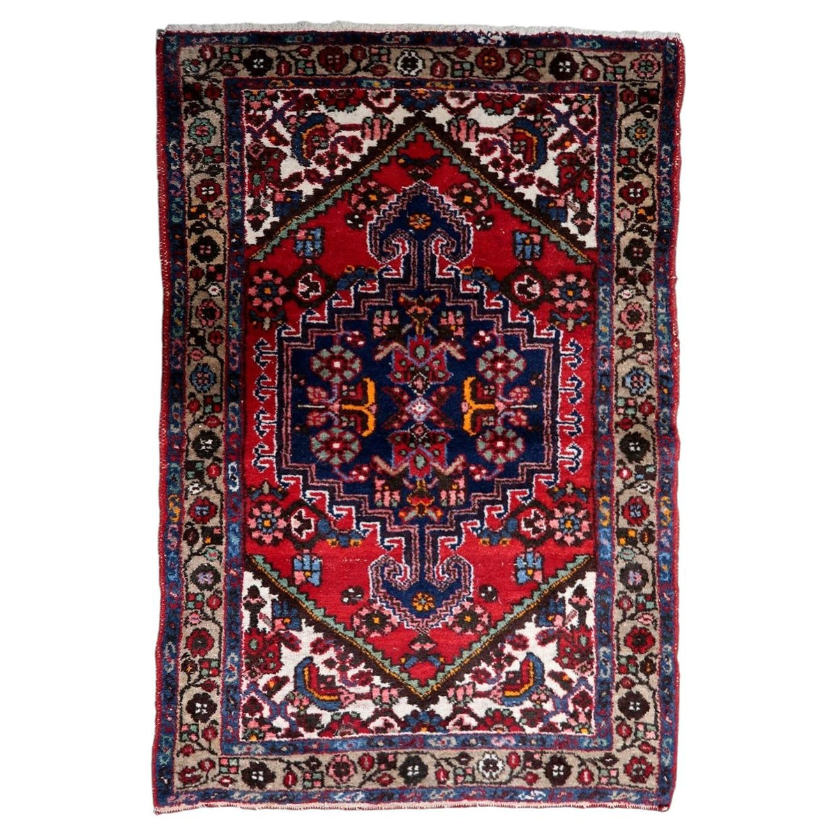 Handmade 1950s wool rug with a striking red and navy medallion design and traditional craftsmanship
