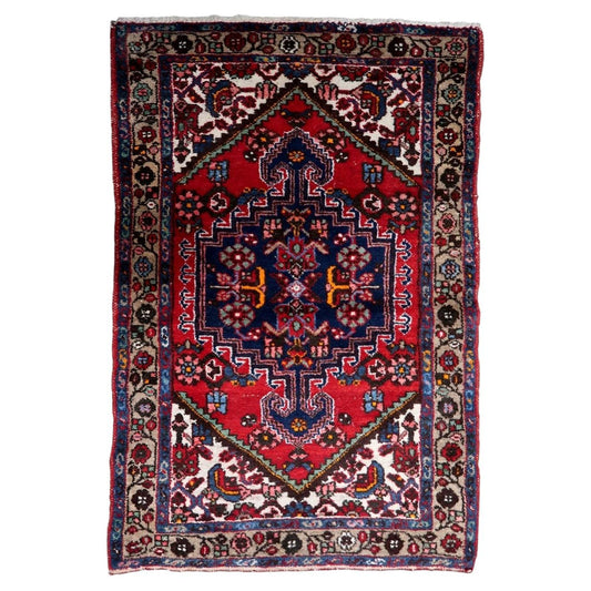 Handmade 1950s wool rug with a striking red and navy medallion design and traditional craftsmanship