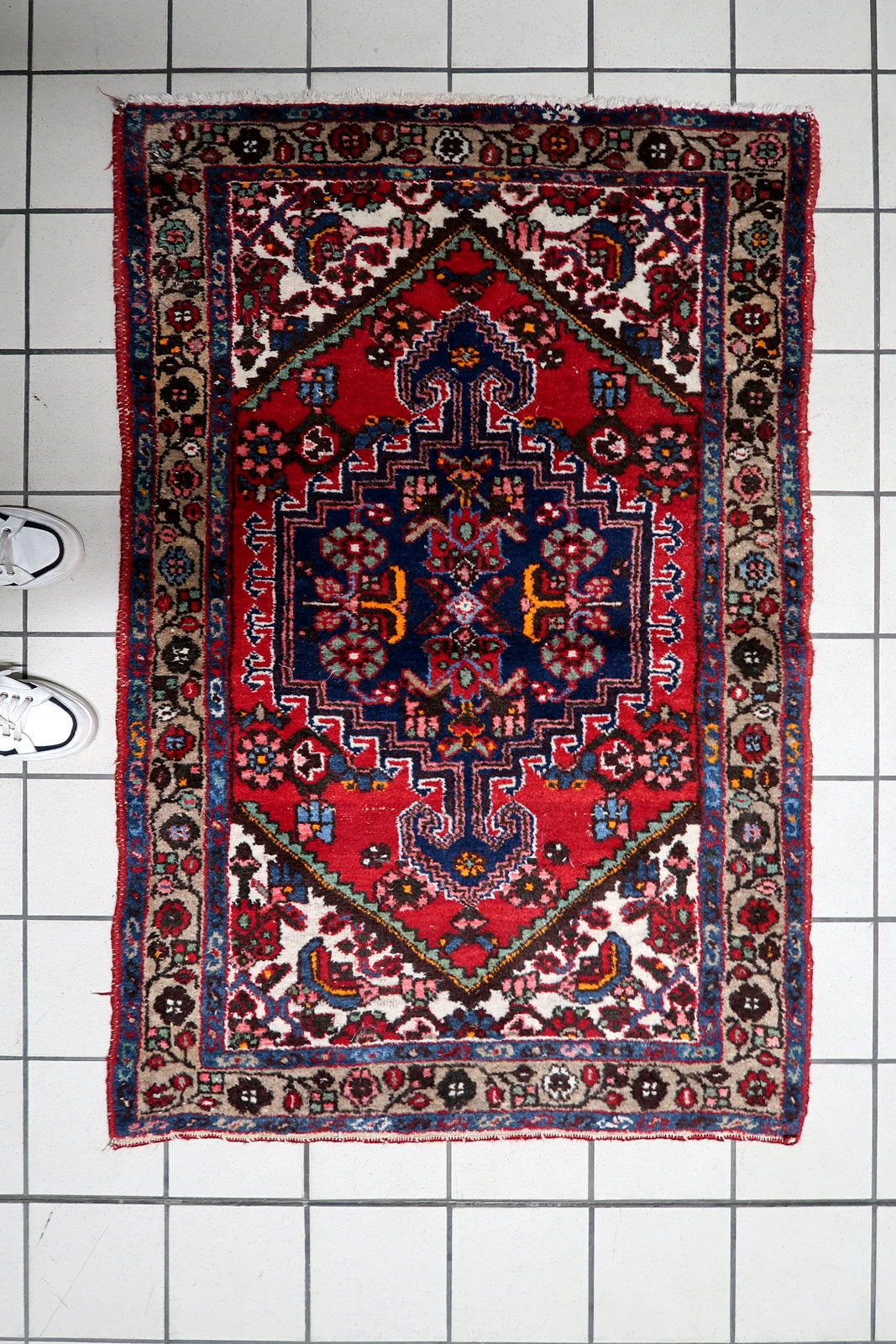 Vintage wool area rug featuring a bold central medallion in rich red and deep navy tones