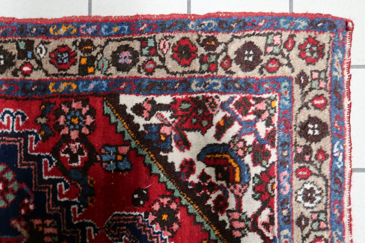 Handwoven mid-century carpet with intricate floral motifs surrounding a decorative medallion centerpiece