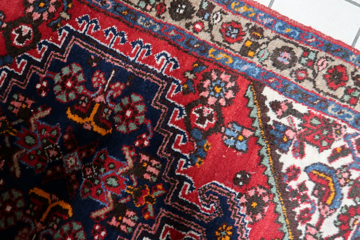 Traditional red and navy wool rug from the 1950s showcasing classic Persian-inspired ornamentation
