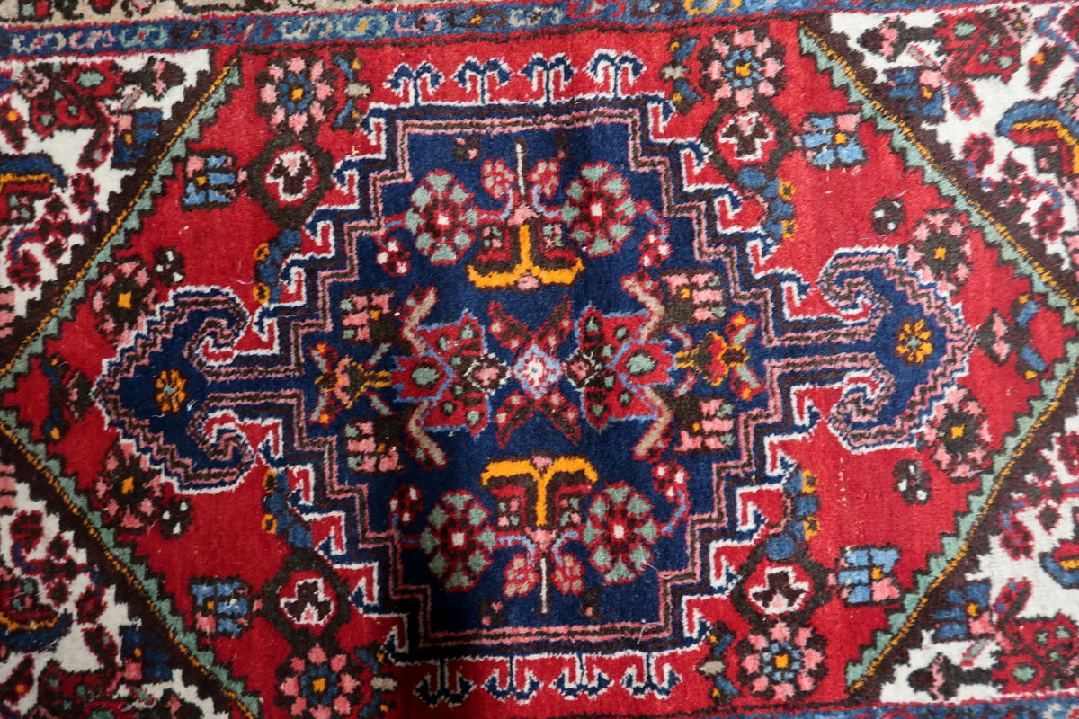 Vintage wool carpet featuring a vibrant red field accented by navy blue decorative motifs