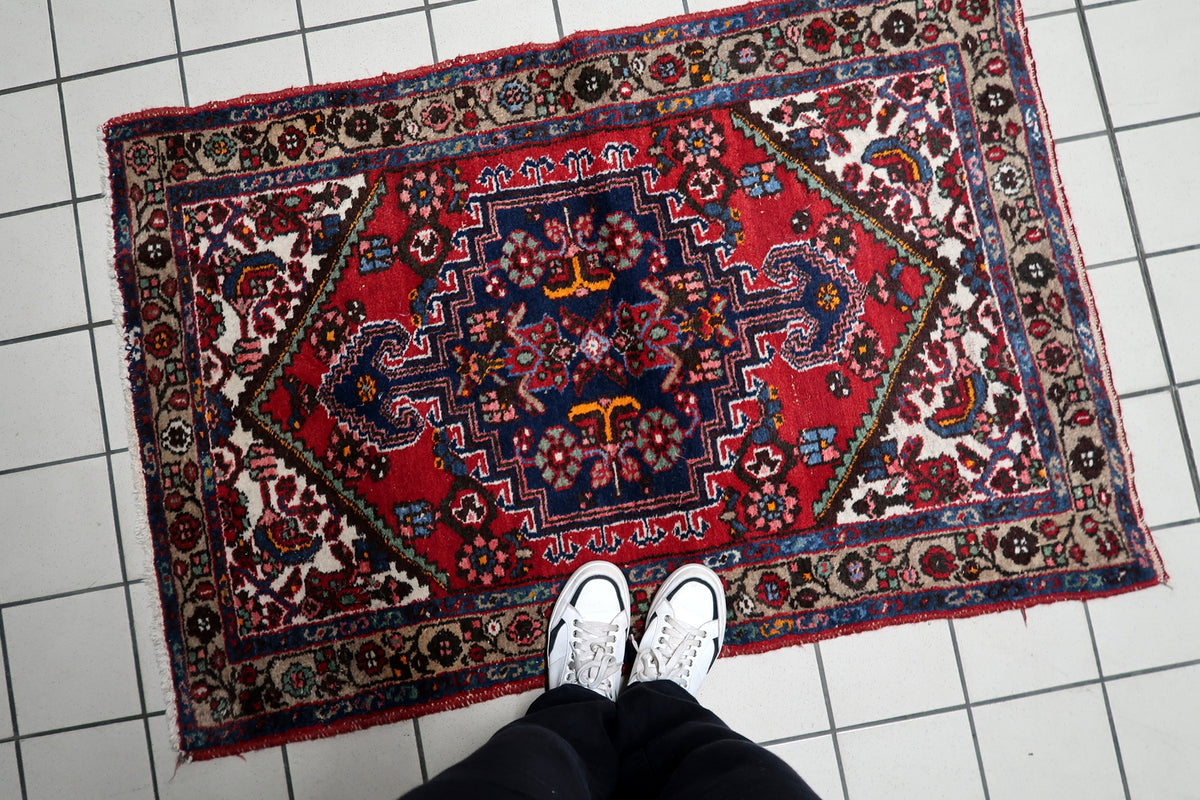 Traditional handmade rug in red and navy with finely woven motifs and balanced symmetry
