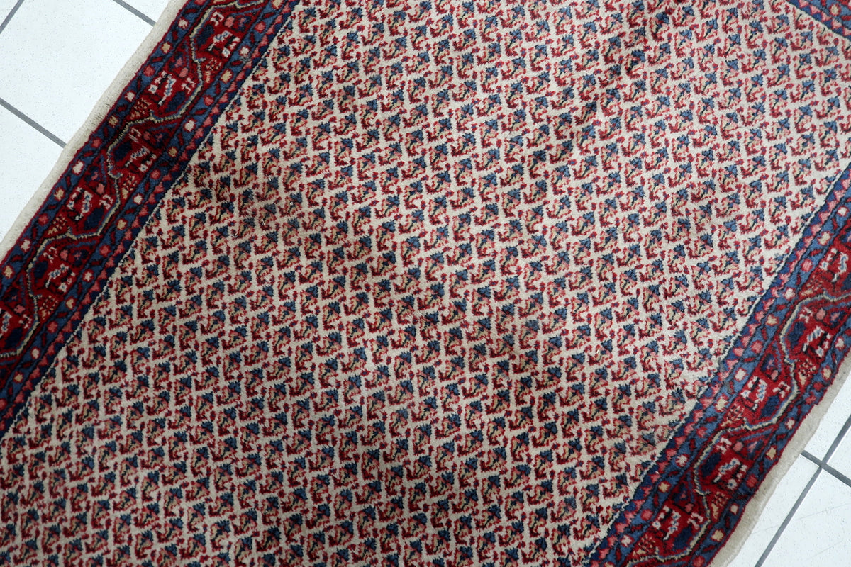Warm cream ivory and deep madder red color palette on a vintage 1950s hand-knotted accent rug.
