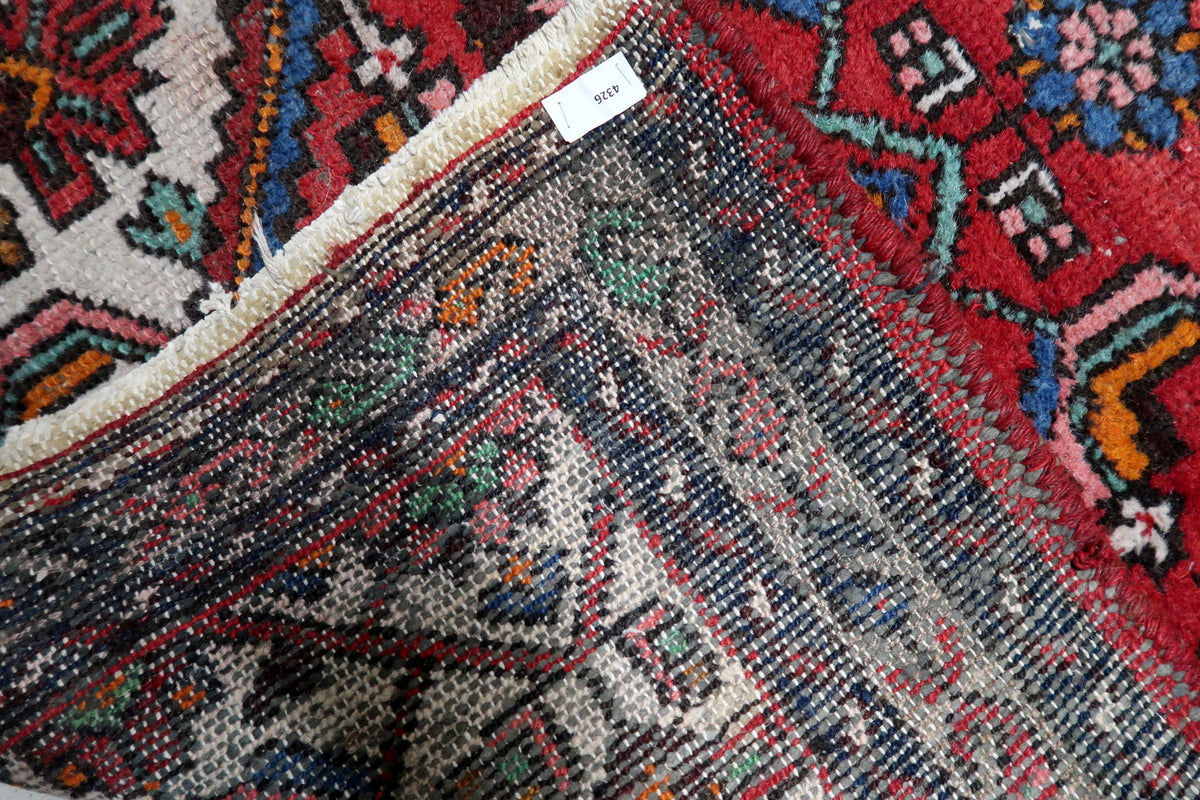 Soft madder root red, deep navy blue, ivory, and subtle terracotta dye tones on an antique Persian medallion rug.