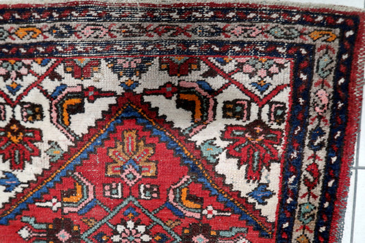 Hand-knotted antique 1920s Persian area rug featuring a central floral medallion on a rich red wool field.