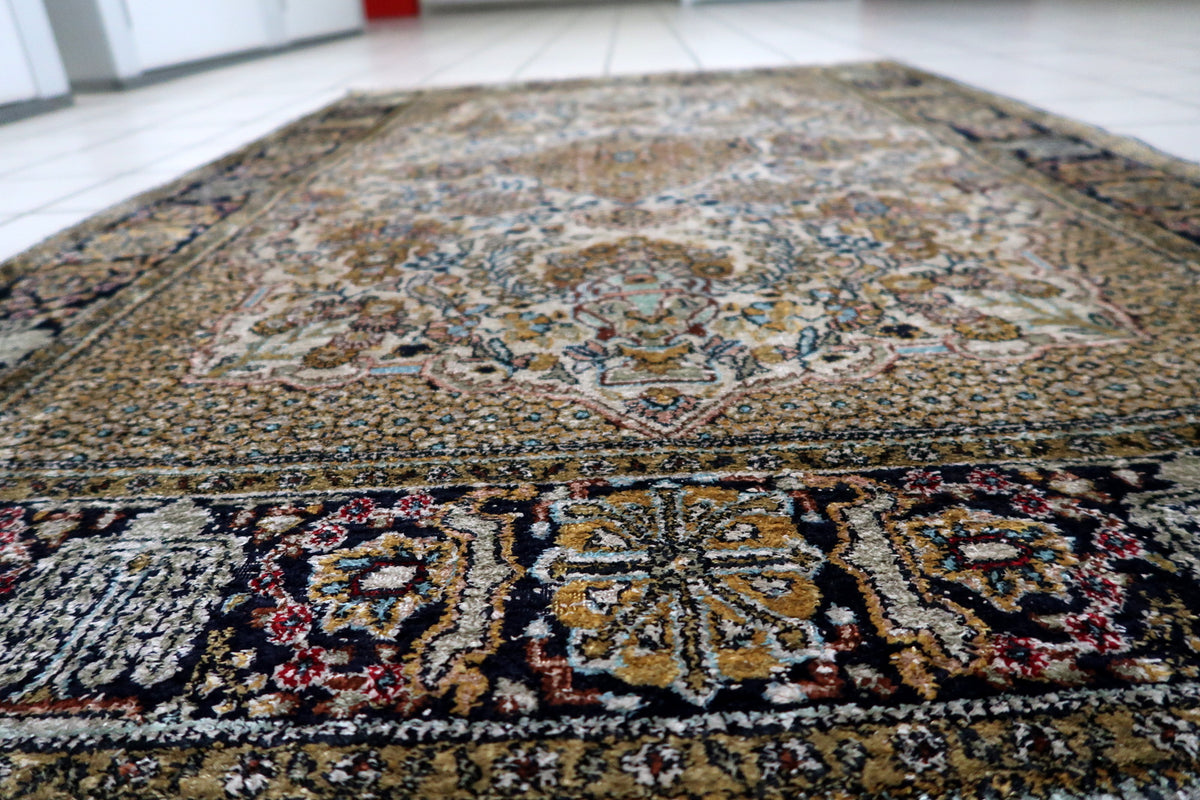 Lustrous natural silk fibers reflecting light across the smooth pile surface of an antique-style Kashmir carpet.