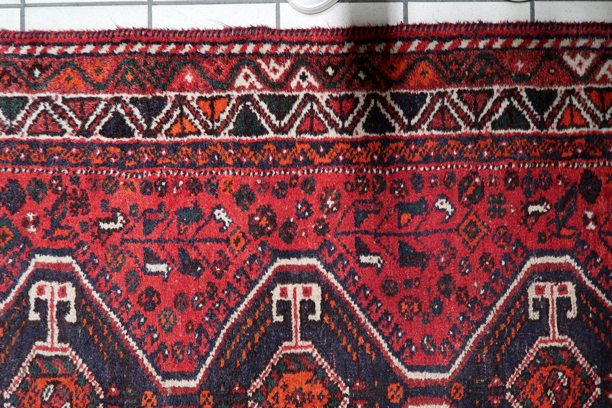 Multi-band framing border with repeating geometric rosettes and decorative guard bands on a 1930s wool rug.