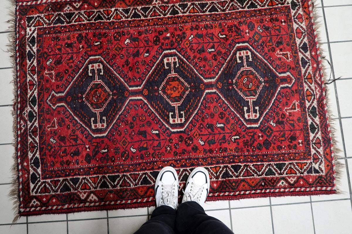 Warm terracotta, deep navy indigo, ivory, and soft earth tones on an antique 1930s handmade wool rug.