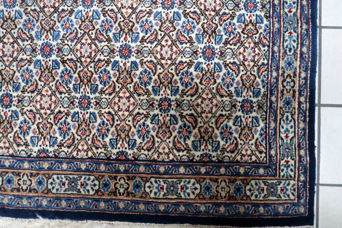 Hand-knotted 1950s oriental accent rug displaying a delicate floral pattern on an ivory field with navy blue borders.