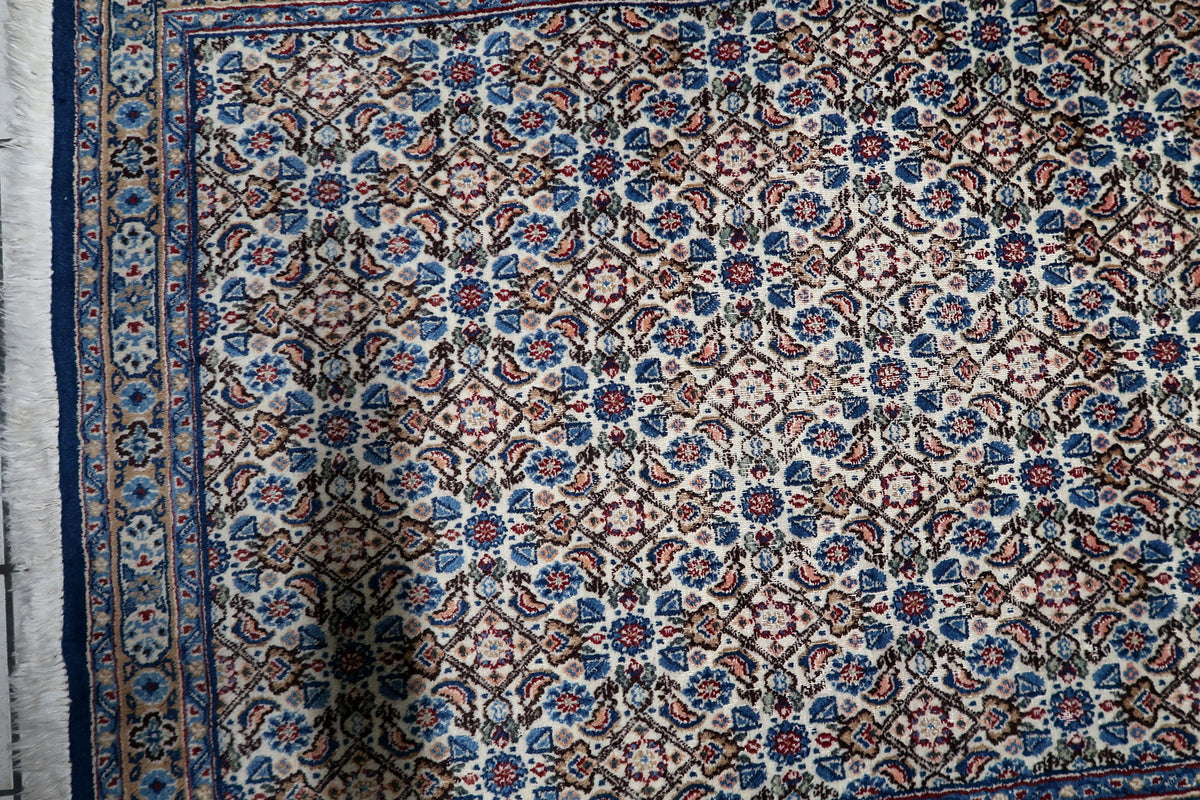 Multi-band framing border with repeating floral rosettes and classic guard bands on a 1950s hand-knotted wool rug.