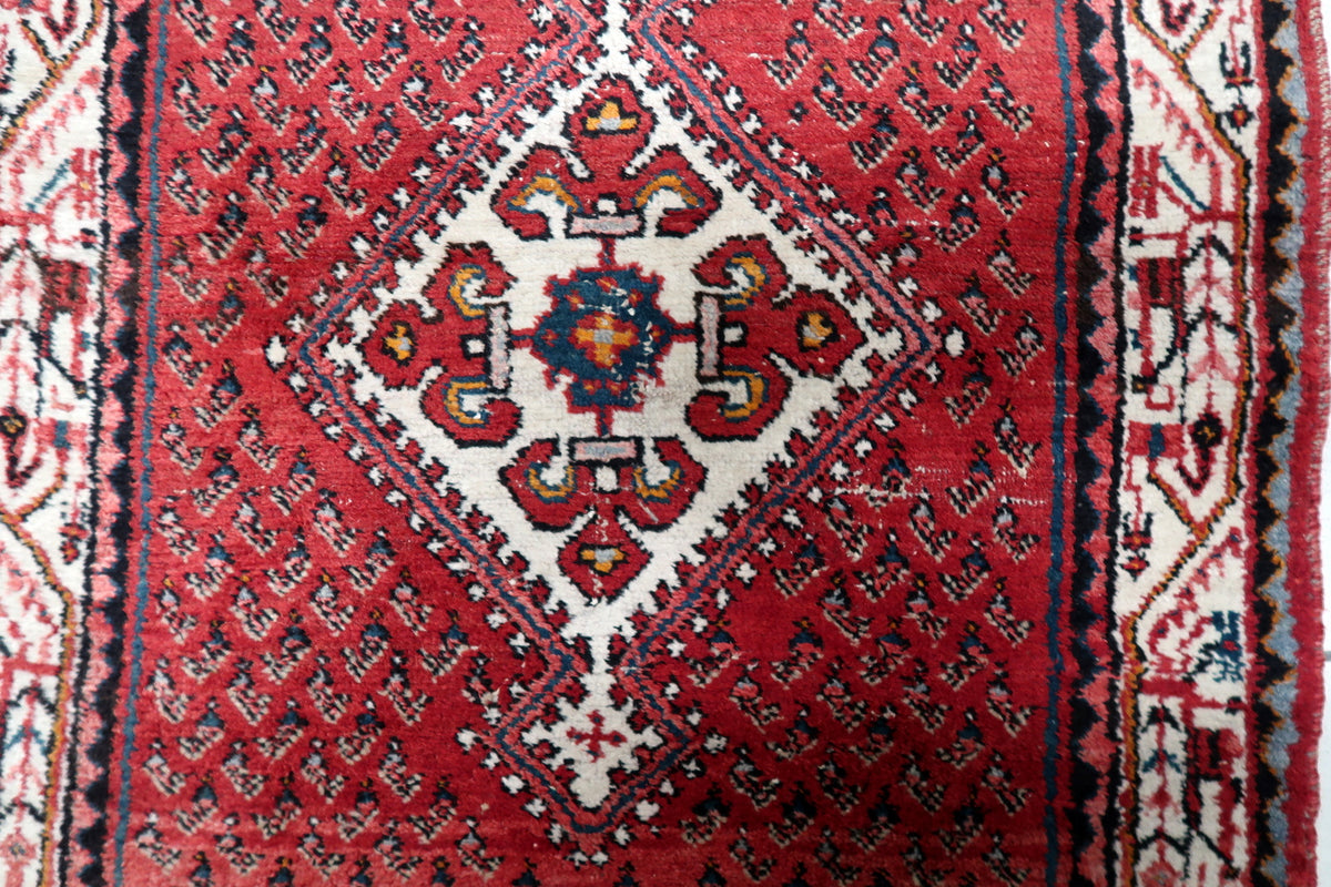 Detailed central floral medallion surrounded by delicate arabesques, palmettes, and trailing vine scrollwork on a red field.