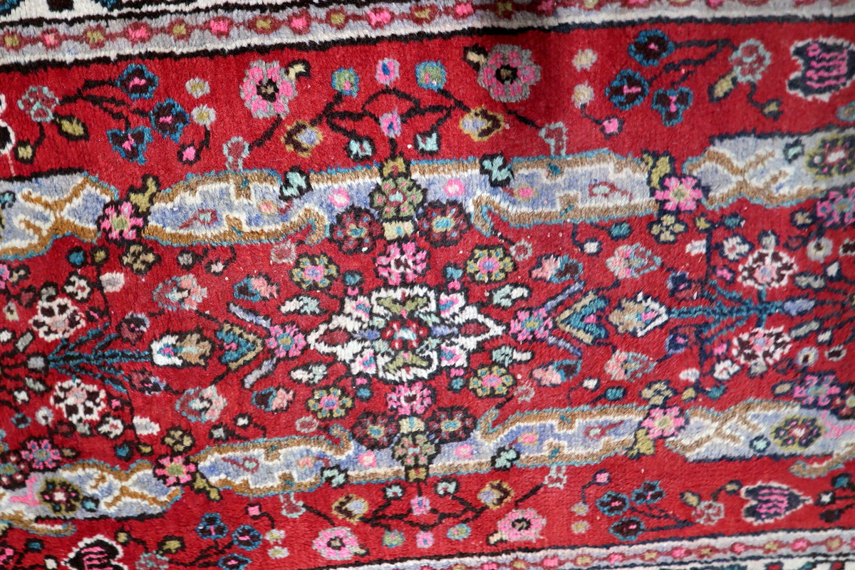 Multi-band framing border with repeating floral rosettes, classic guard bands, and geometric vine motifs on a 1950s wool rug.