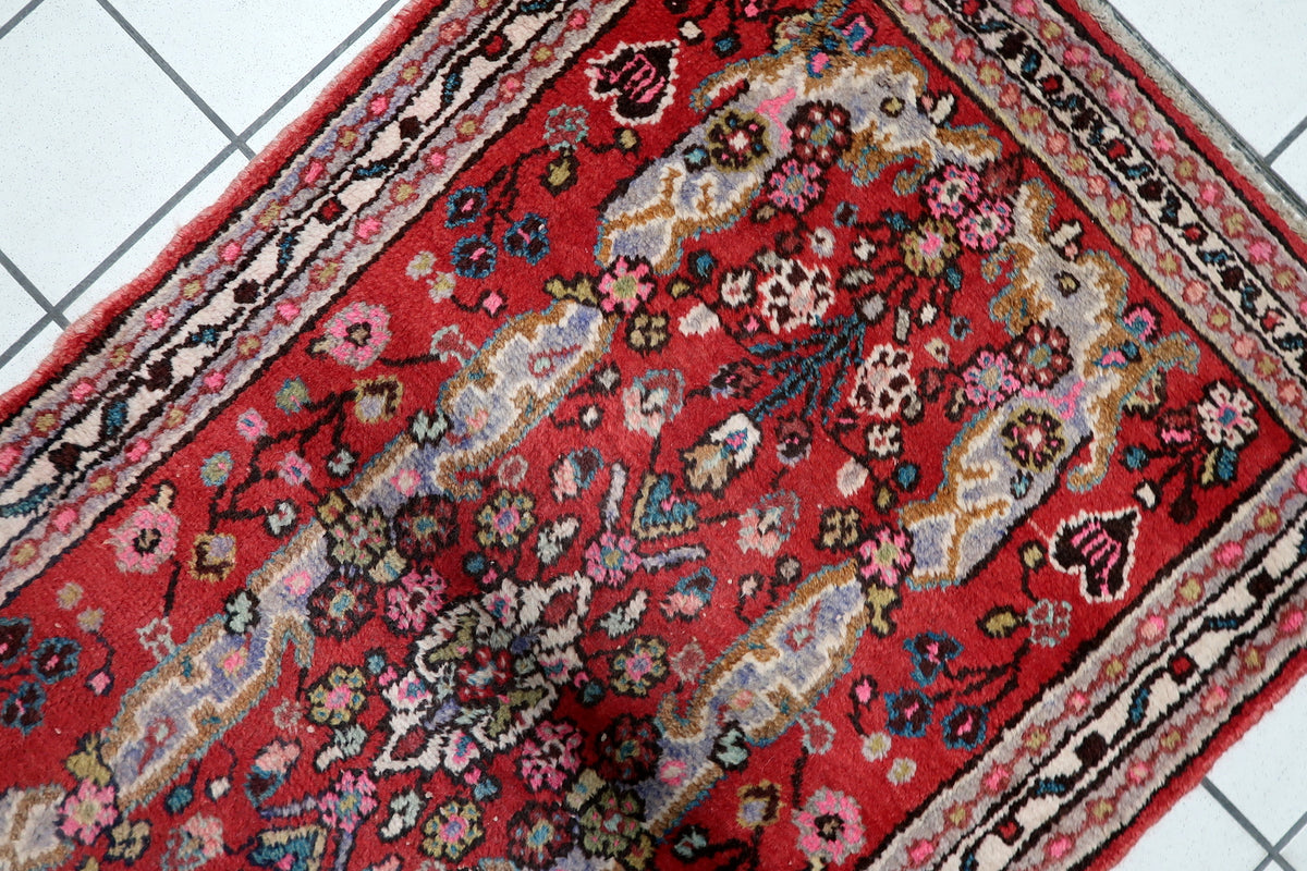Deep crimson red, warm cream ivory, navy indigo, and subtle earth tones on a mid-20th-century handmade wool rug.
