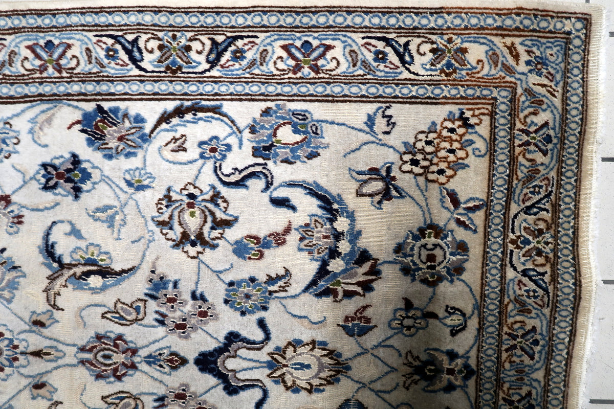 Hand-knotted mid-century oriental accent rug displaying intricate botanical patterns on an ivory field with rich blue borders.