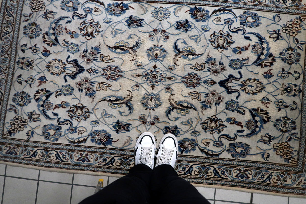 Multi-band framing border with repeating floral rosettes and classic guard bands on a hand-knotted 1950s wool rug.