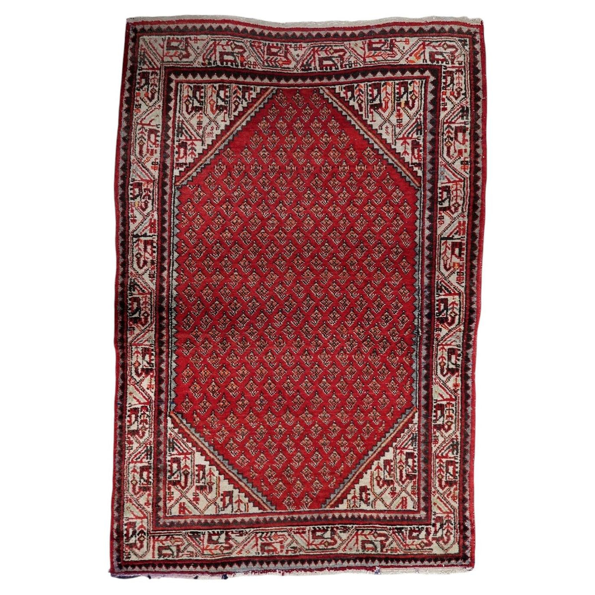 Vintage 1950s handmade Indian wool area rug featuring a traditional boteh and paisley pattern on a rich red and ivory field (Ref: 1C1299).