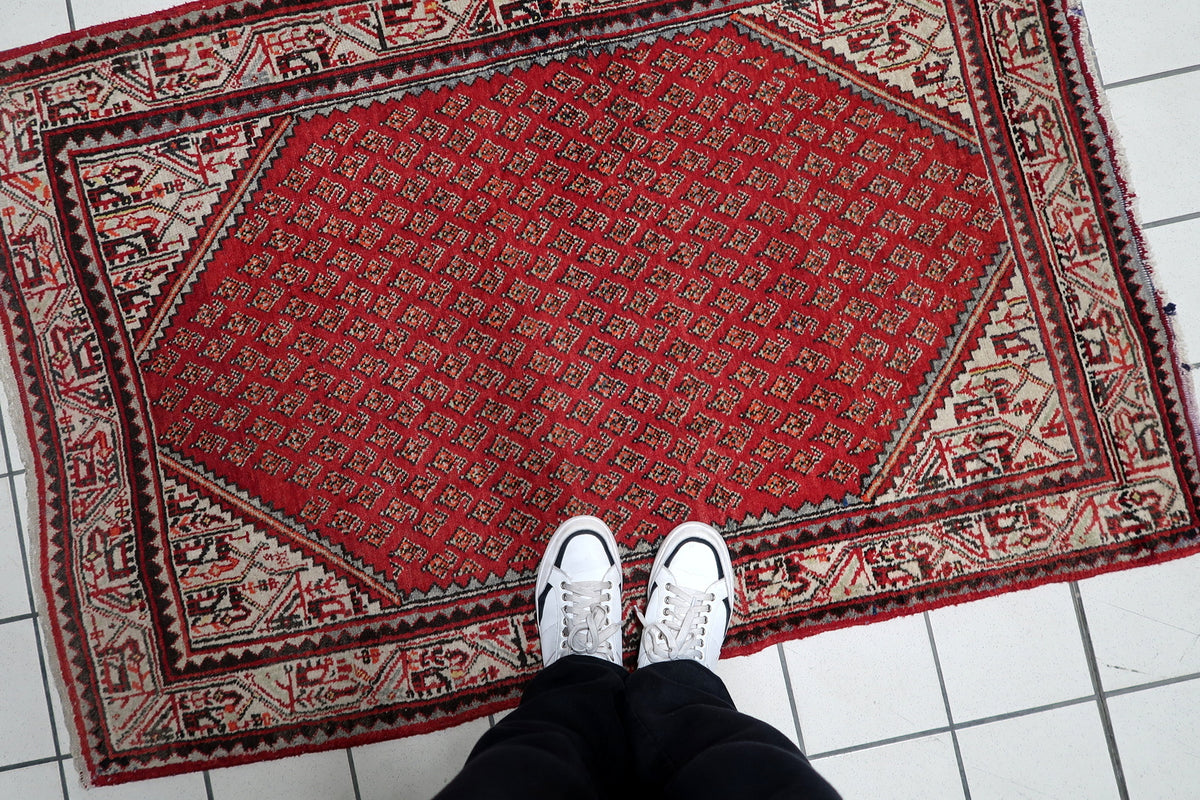 Hand-knotted 1950s oriental accent rug displaying repeating teardrop boteh motifs with intricate floral borders.