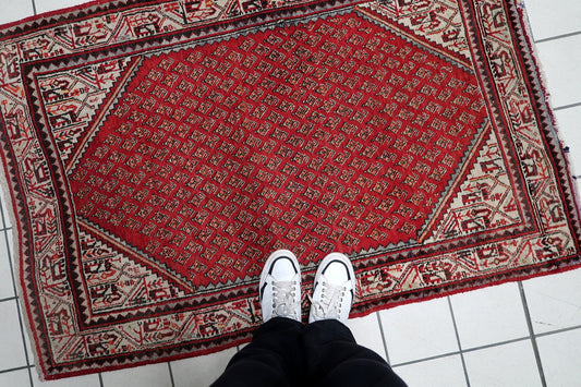 Hand-knotted 1950s oriental accent rug displaying repeating teardrop boteh motifs with intricate floral borders.