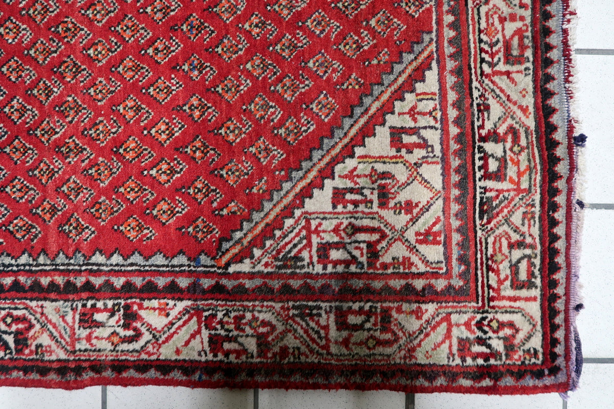 Mid-century vintage Indian wool carpet featuring crimson red, warm ivory, and navy blue color palette with natural fiber luster.