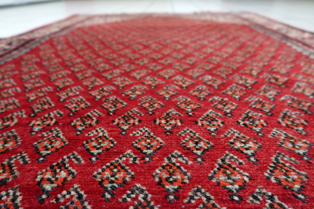 Deep crimson red, warm cream ivory, indigo blue, and subtle earth tones on a mid-20th-century handmade wool rug.