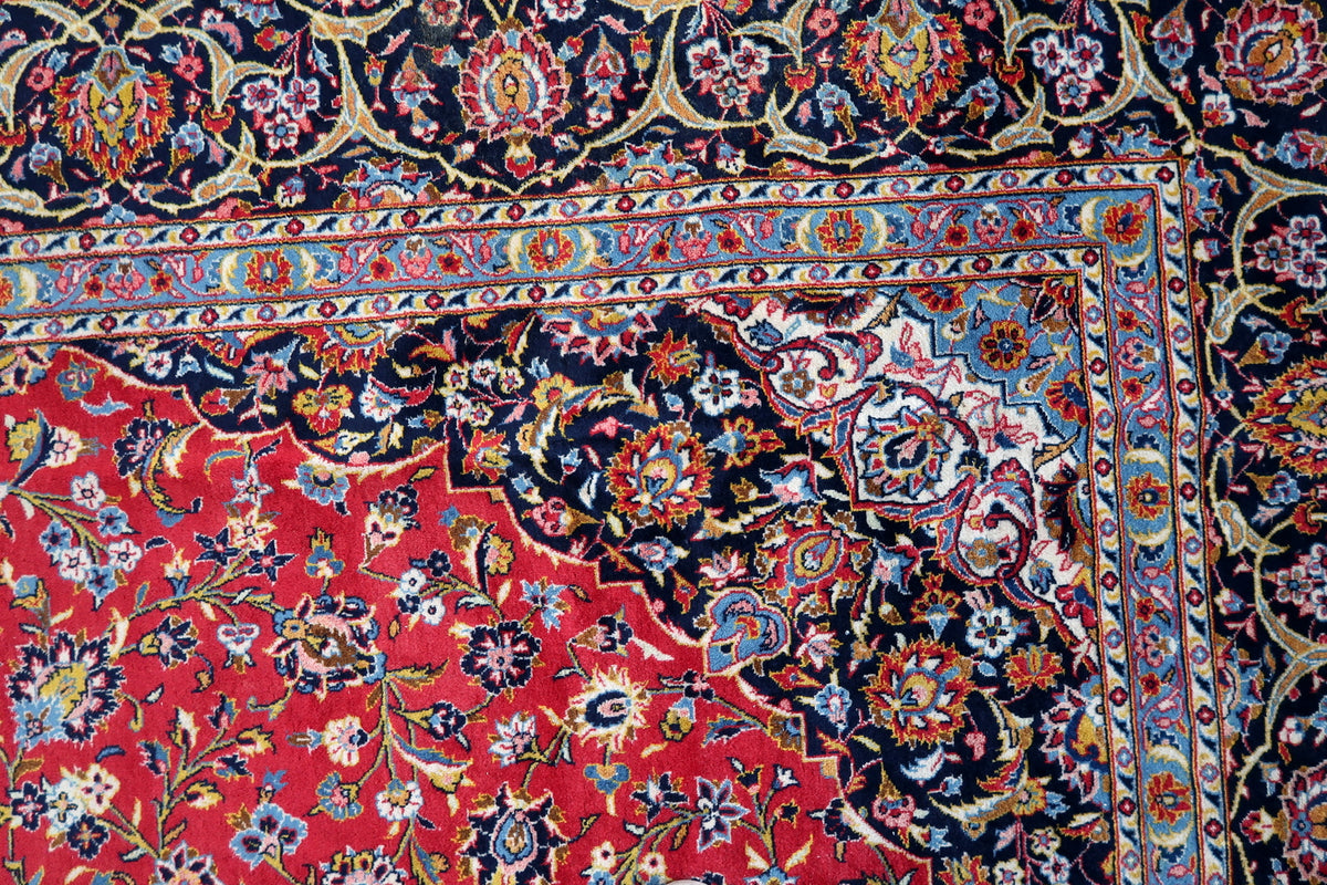 Red field and scalloped navy corner with dense pink, ivory and blue floral ornament