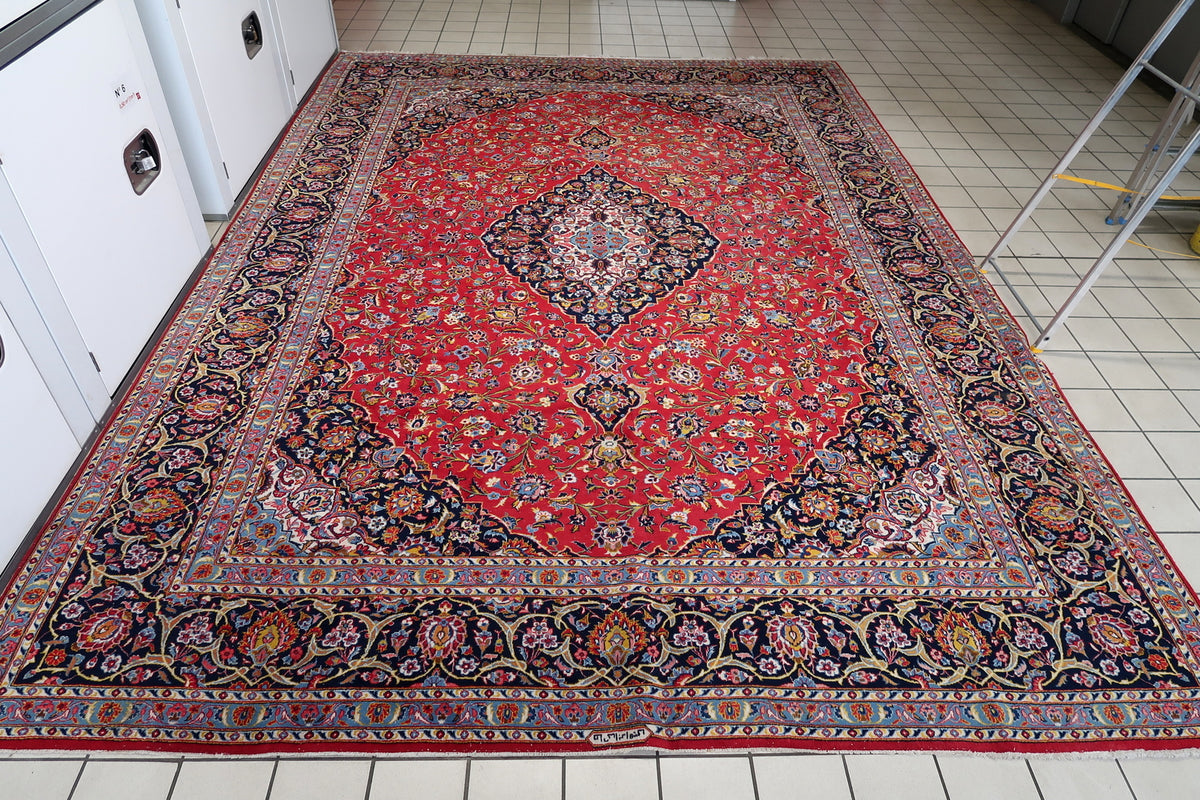 Full-length view of the red and navy wool rug showing medallion and all floral borders