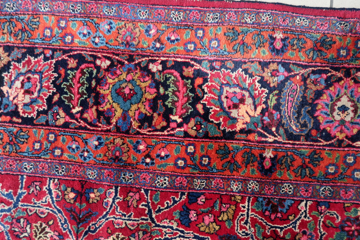 Navy main border with multicoloured palmettes between rust-red floral bands