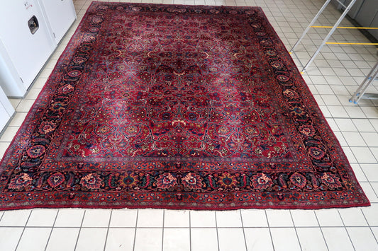 Full-length view of red wool rug with scrolling arabesques and layered floral borders