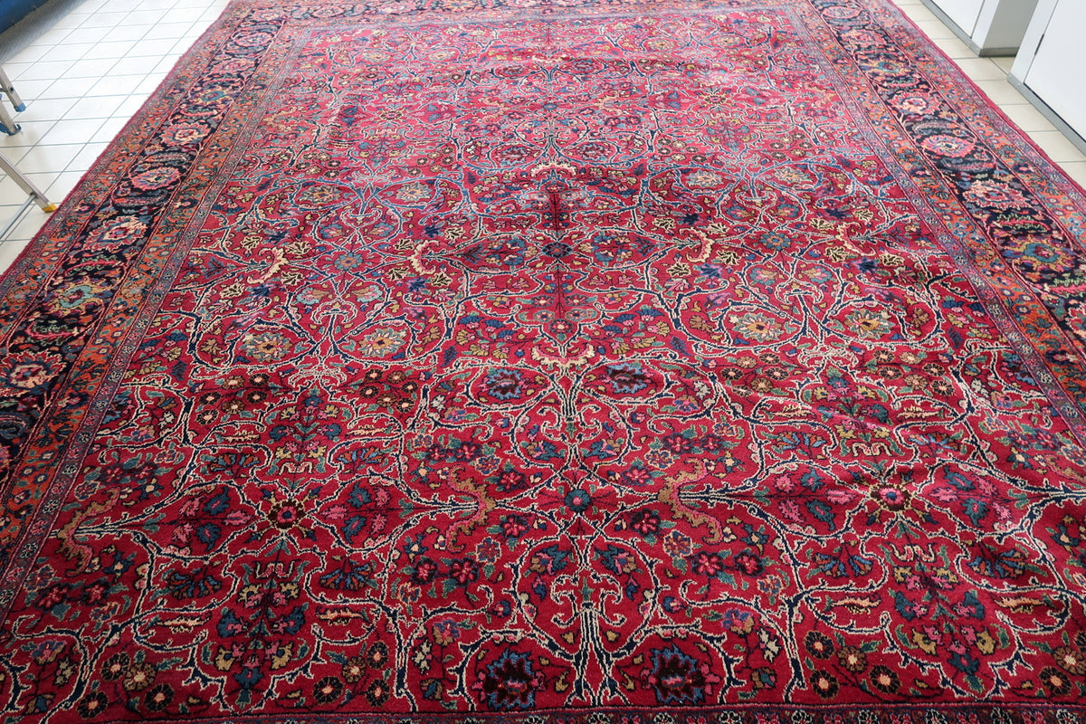 Lengthwise detail of ivory-outlined floral arabesques across the red field