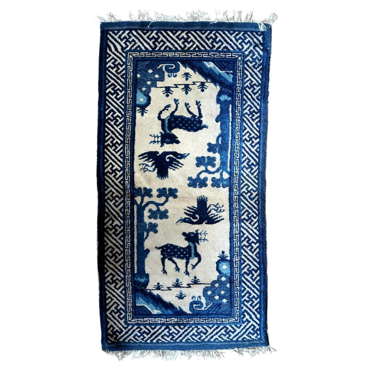 Full view of antique Chinese PaoTao wool rug with spotted deer, birds and blue fretwork borders