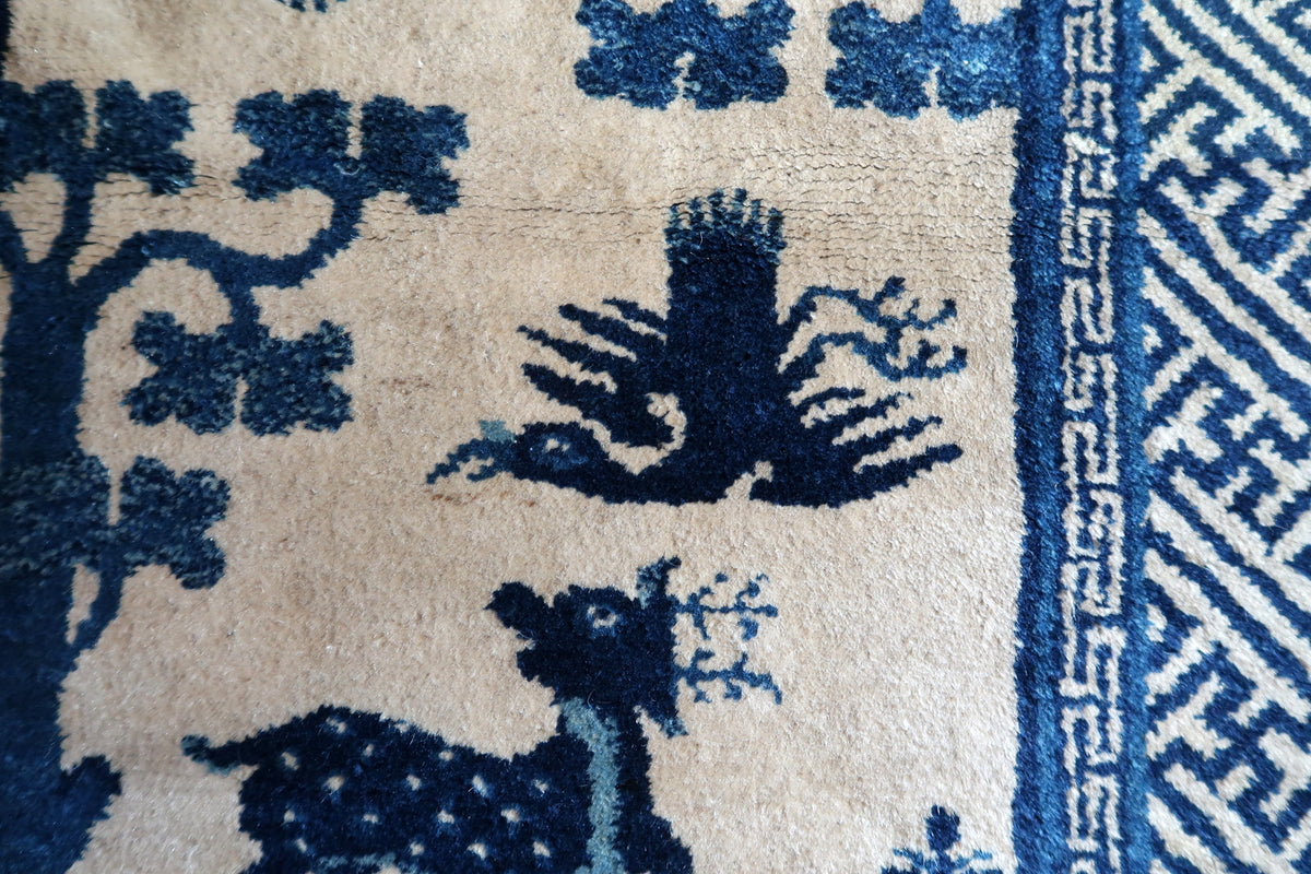Dark blue bird with outstretched wings beside a stylised tree and narrow key border