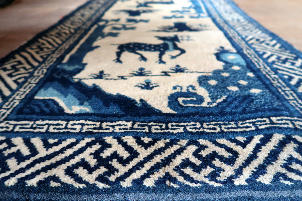 Low-angle detail of blue landscape forms, spotted deer and geometric fretwork border